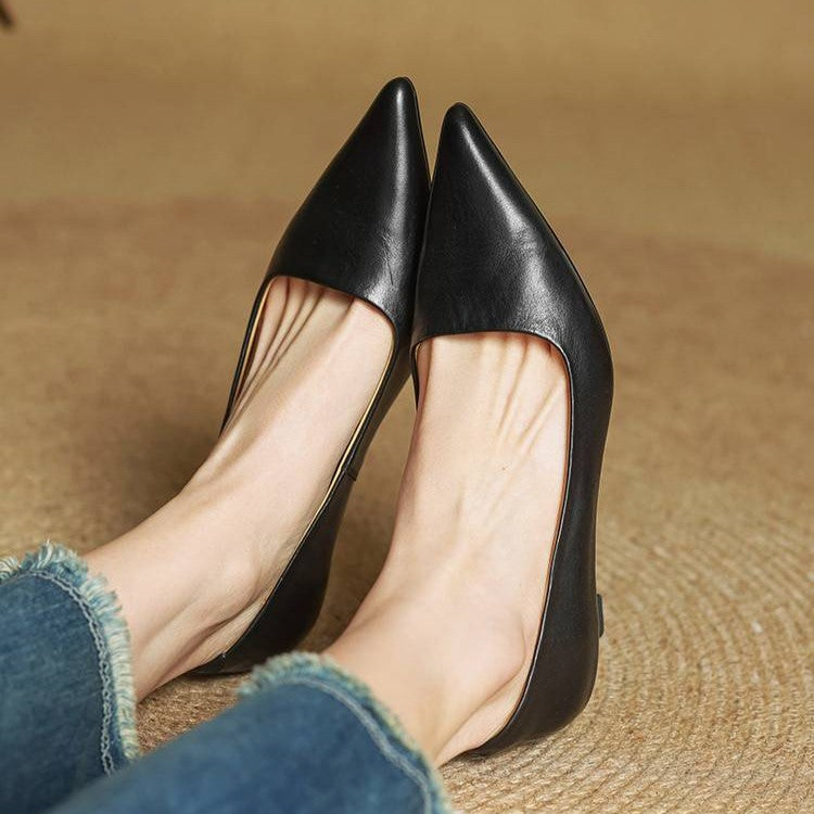 Close-up of a model's feet in black pointed-toe pumps, legs crossed, with jeans 15