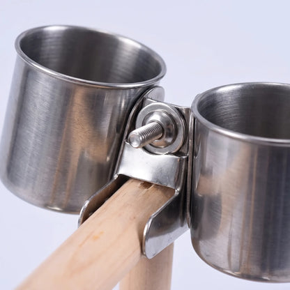 Close-up of the two stainless steel cups held by a metal clamp with a screw on the wooden perch. 4