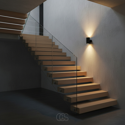 Black wall light on a grey concrete wall beside a floating wooden staircase with glass balustrade, casting light up and down. 4