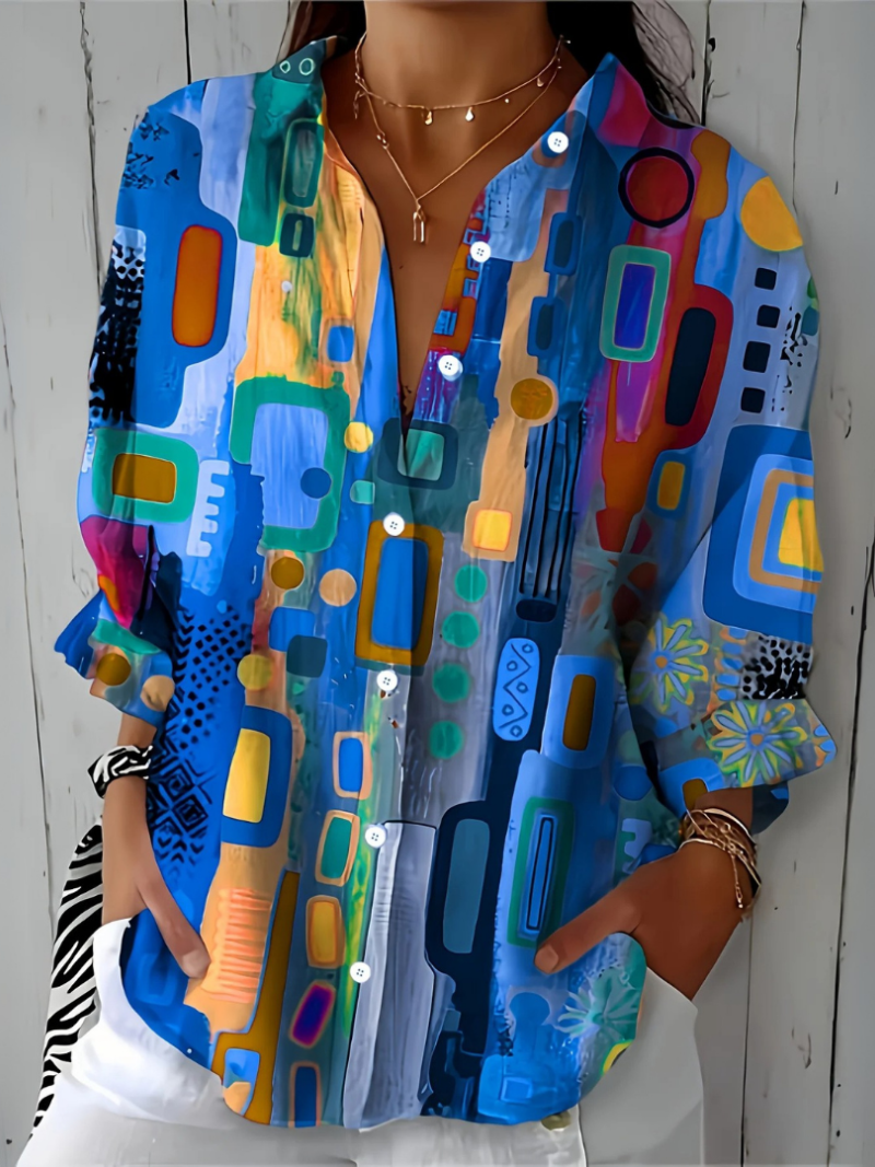 Close-up of the blue version of the blouse showing the open collar, white buttons and painterly abstract print on the sleeves. 6