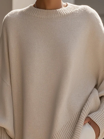 Close-up of the cream jumper's ribbed crew neckline, soft knit texture and batwing shoulder on a model. 2