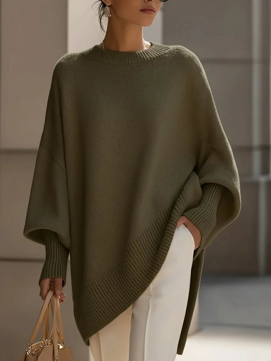 Olive green version of the jumper worn by a model with white trousers, showing the sloping ribbed hem. 7