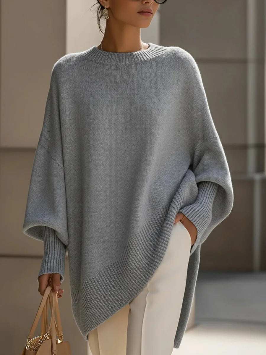 Light grey version of the oversized jumper on a model, with ribbed cuffs and an asymmetric ribbed hem. 9
