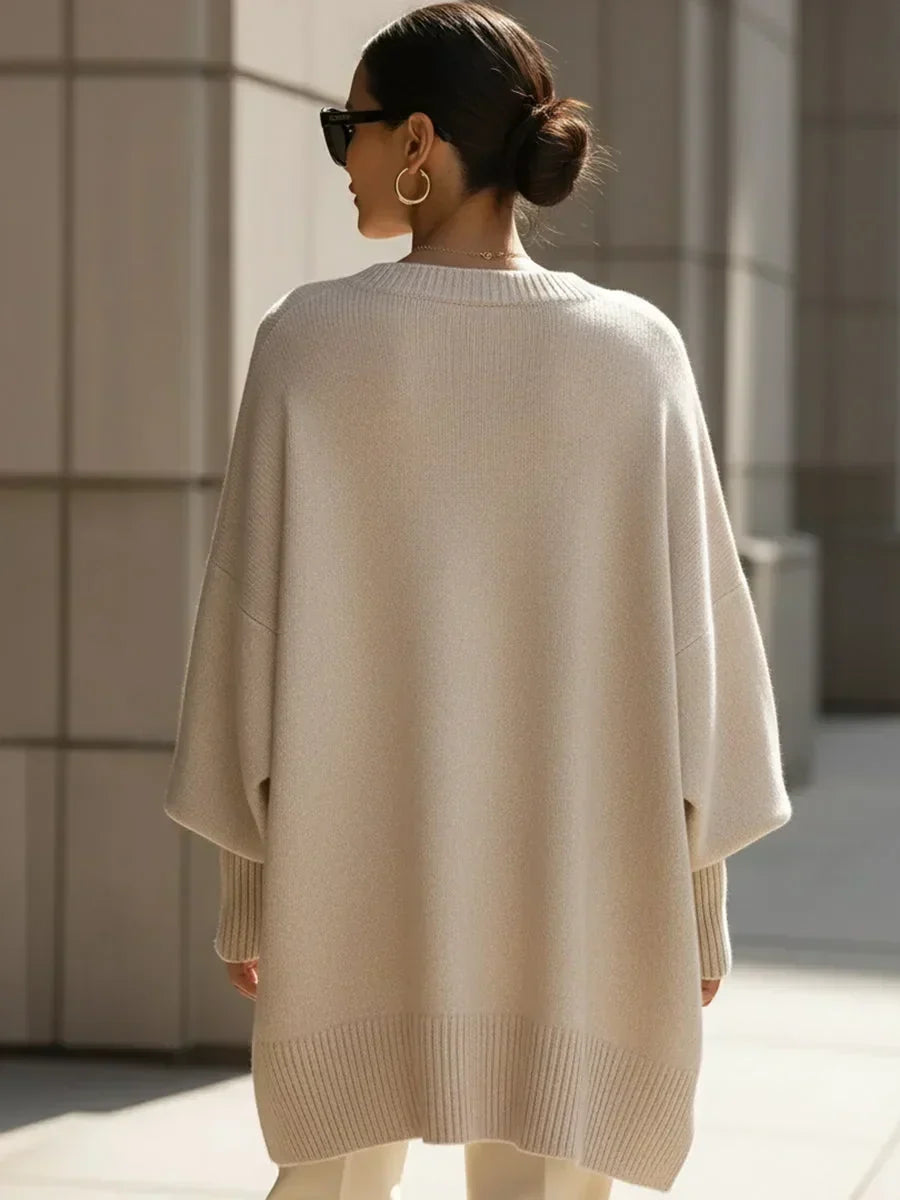 Back view of the cream oversized jumper on a model with a low bun, showing the straight ribbed hem. 4