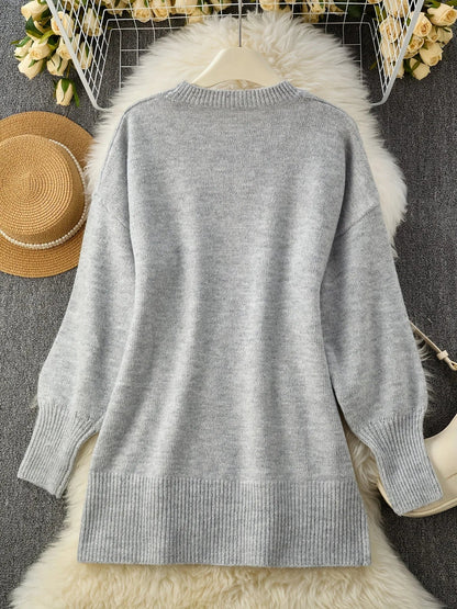 Flat lay of the grey jumper's back on a hanger over a fluffy white rug, with a straw hat nearby. 10