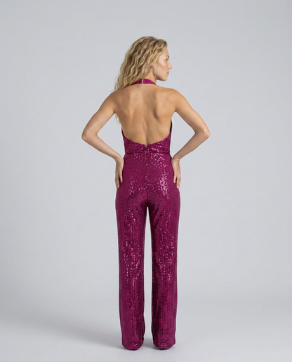 Back view of the magenta sequin jumpsuit with open back, model's hands resting on her hips 18