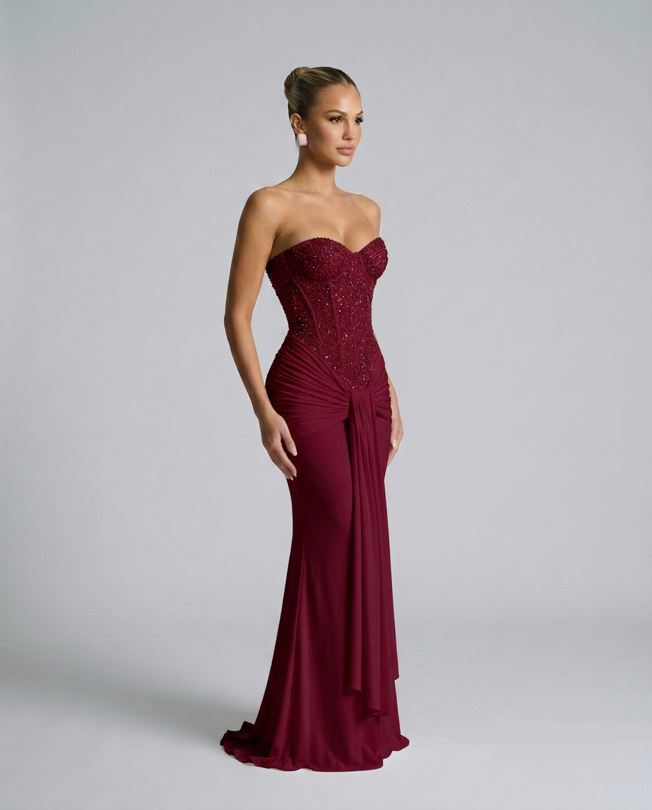 Burgundy beaded corset maxi dress worn in three-quarter view, showing the side drape and flared hem 4