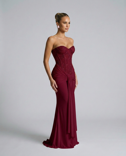Burgundy beaded corset maxi dress worn in three-quarter view, showing the side drape and flared hem 4