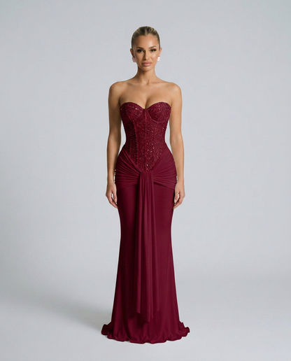 Model facing forward in the burgundy version, with a sparkling beaded bodice and draped waist panel 3
