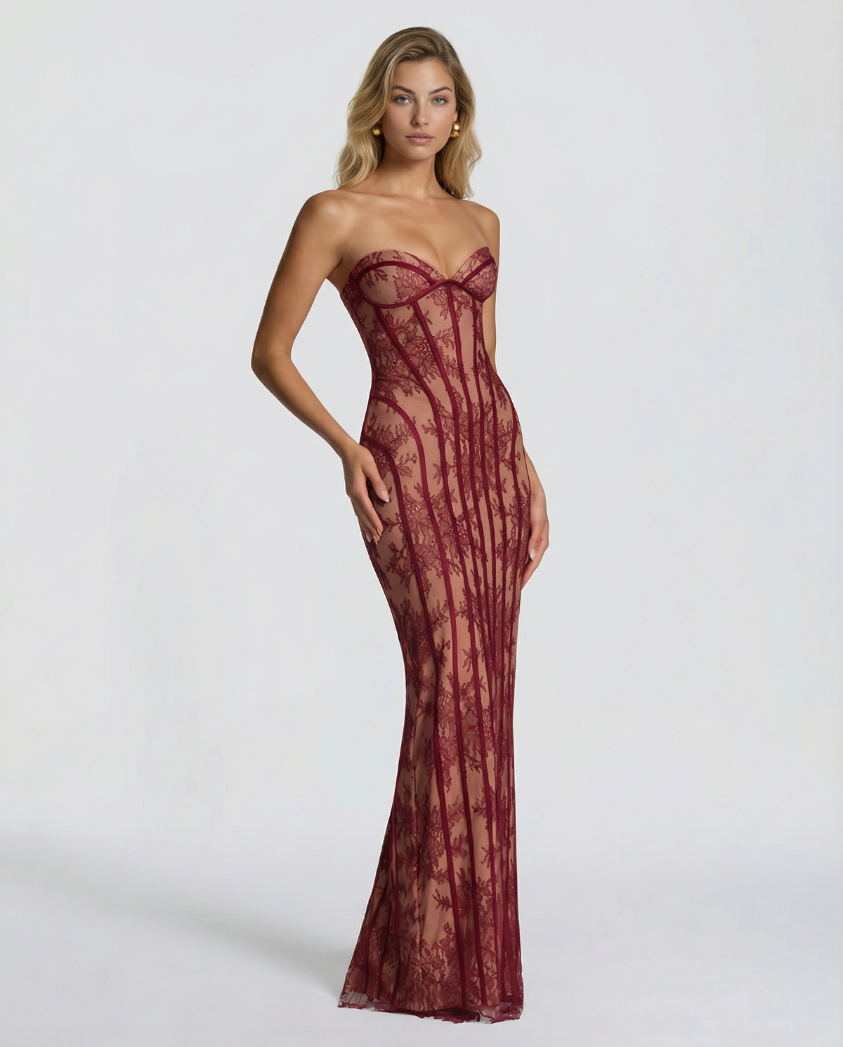 Three-quarter view of the burgundy lace maxi dress with one hand resting on the hip, showing the fitted silhouette. 3