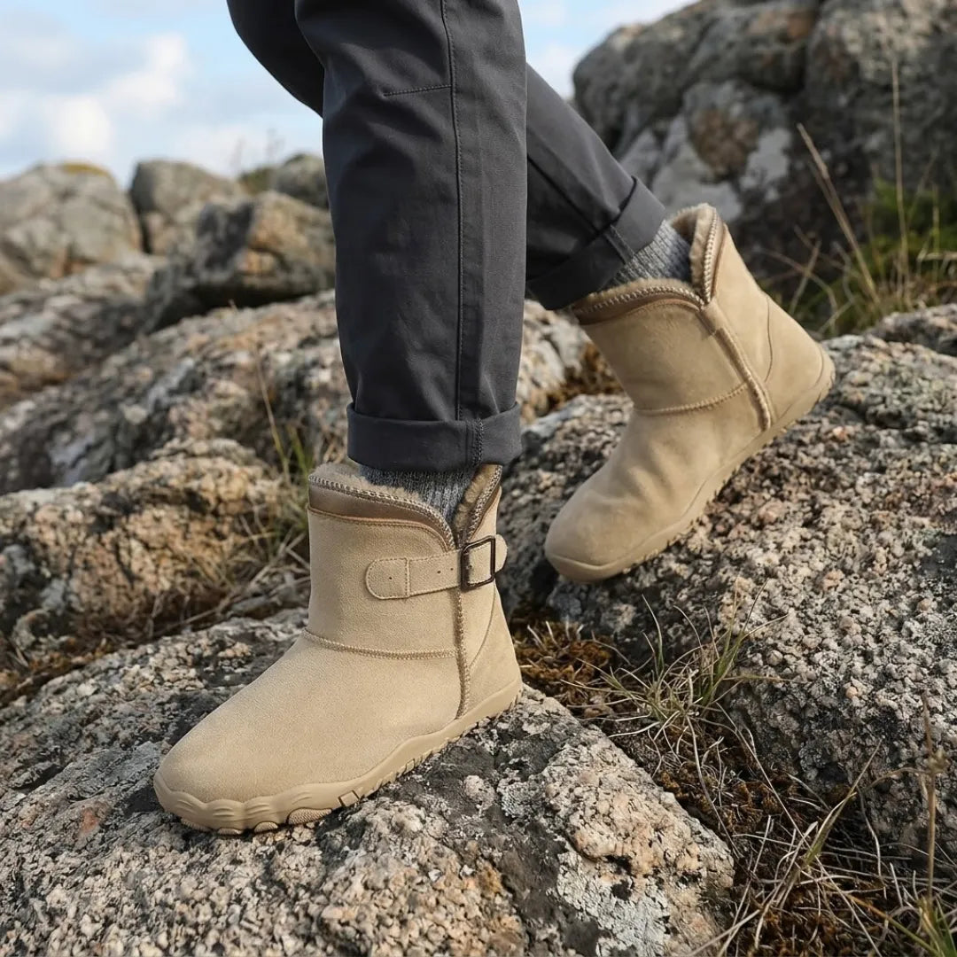 Beige suede boots with fleece collar worn over grey socks while walking across rocky ground 2