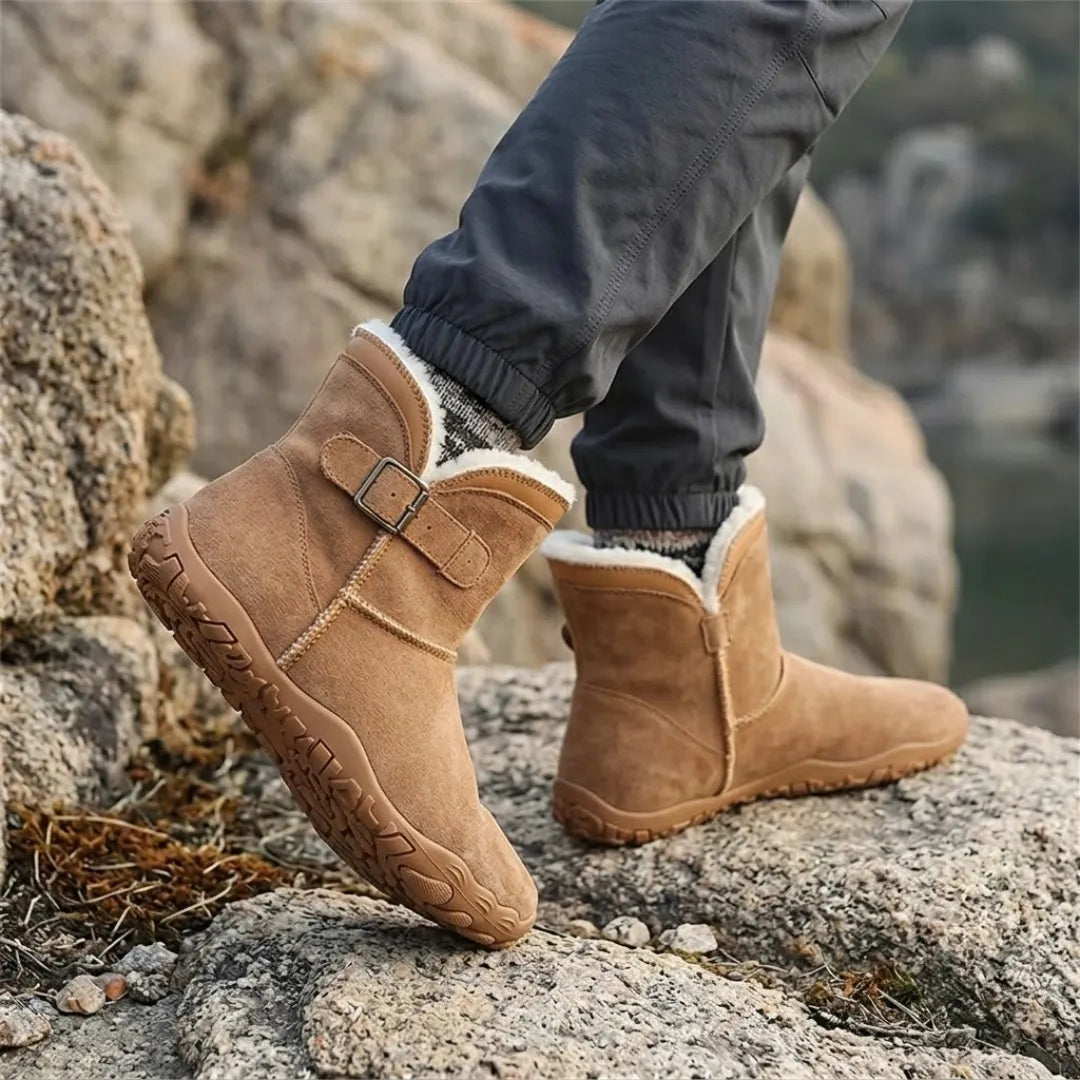 Tan suede boots with cream fleece collar worn with grey trousers while stepping on rocks 20