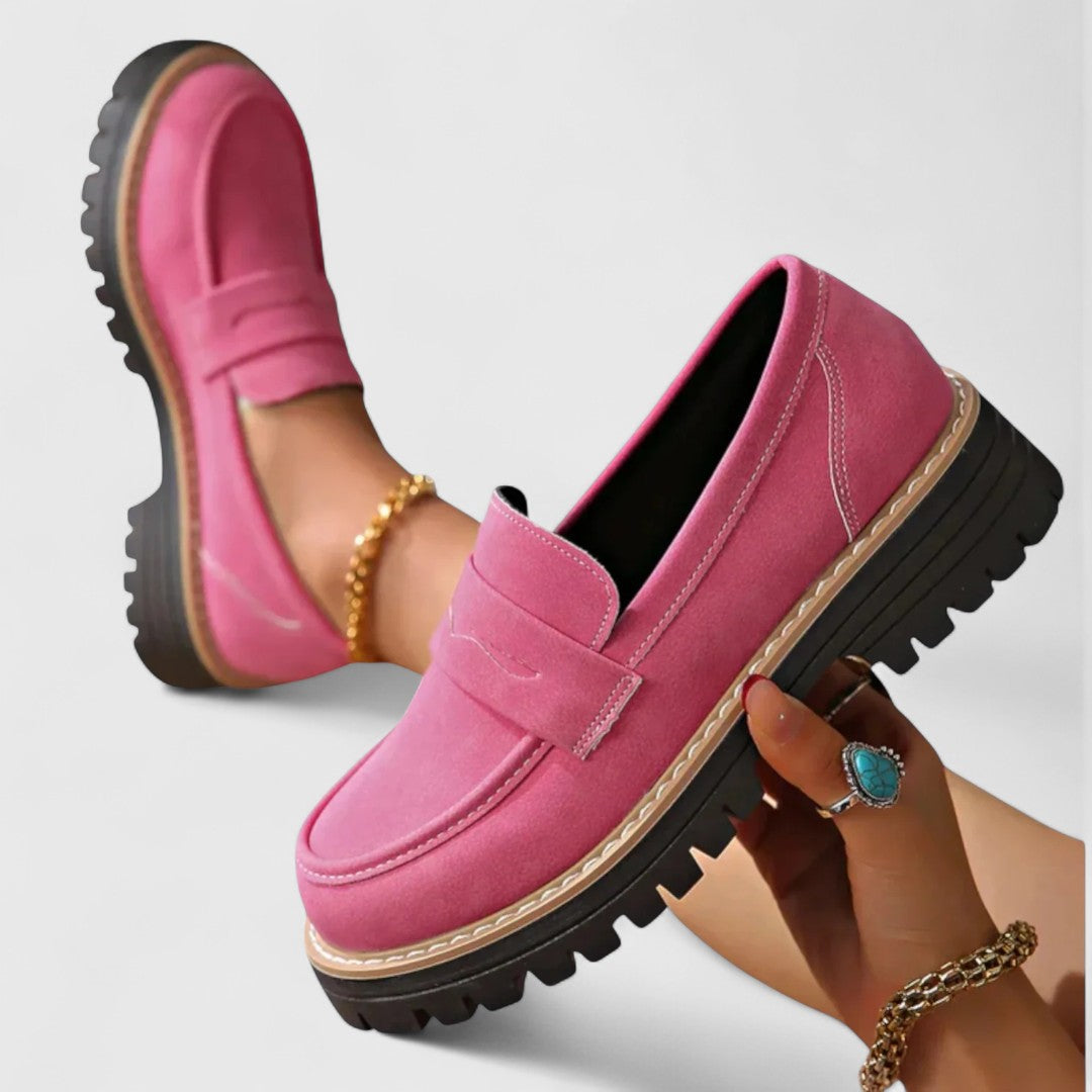 Bright pink loafers held up in one hand, showing the stitched strap and thick lugged sole 3