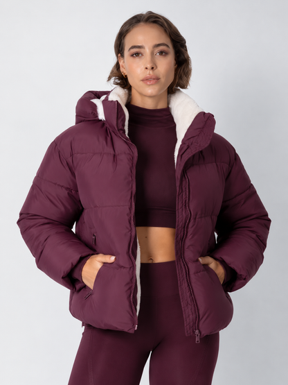 Model wears the deep burgundy puffer jacket open over a matching crop top, cream fleece lining showing 16