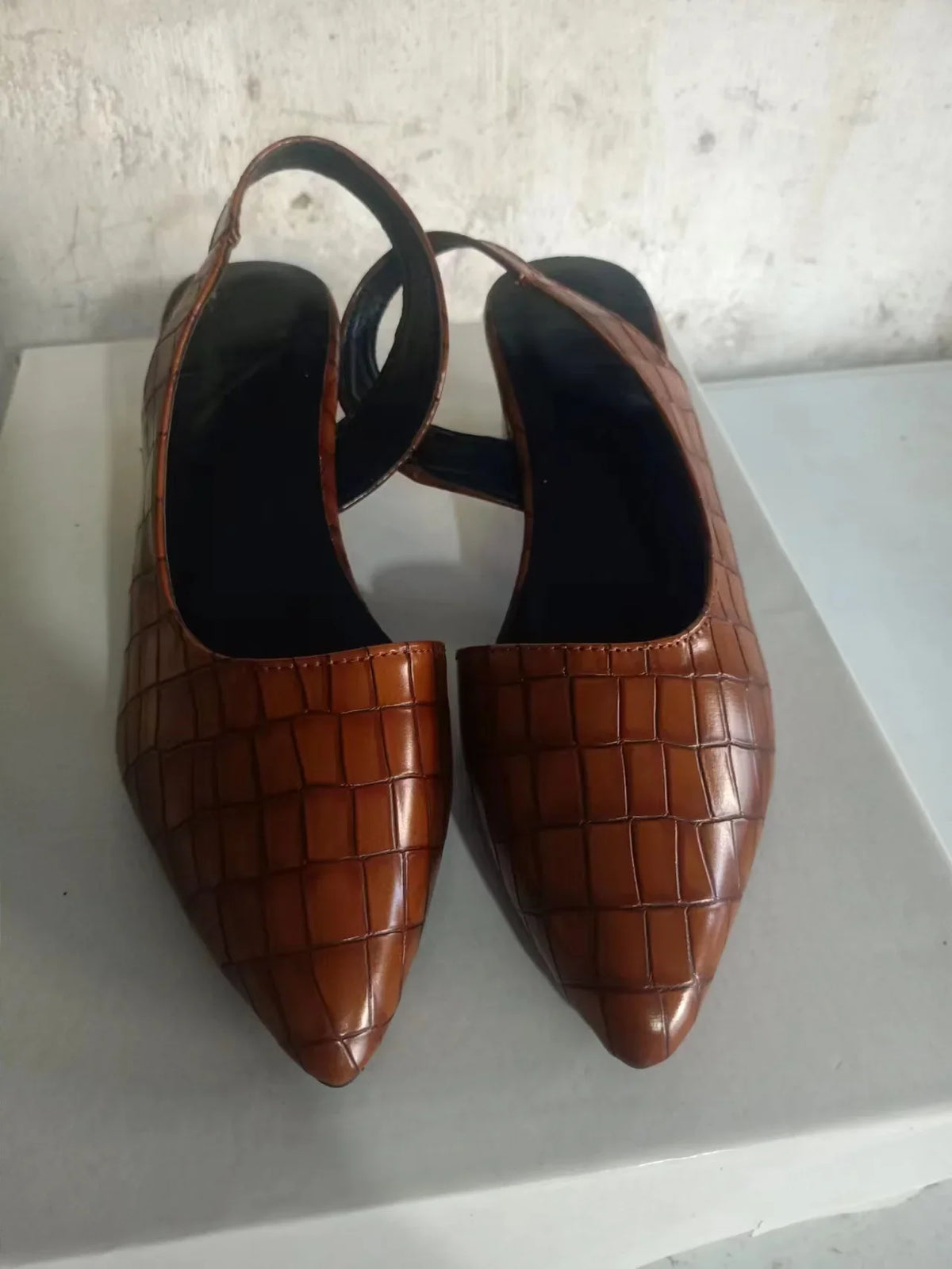 Pair of brown croc-effect slingbacks seen from above on a white box, showing pointed toes 7