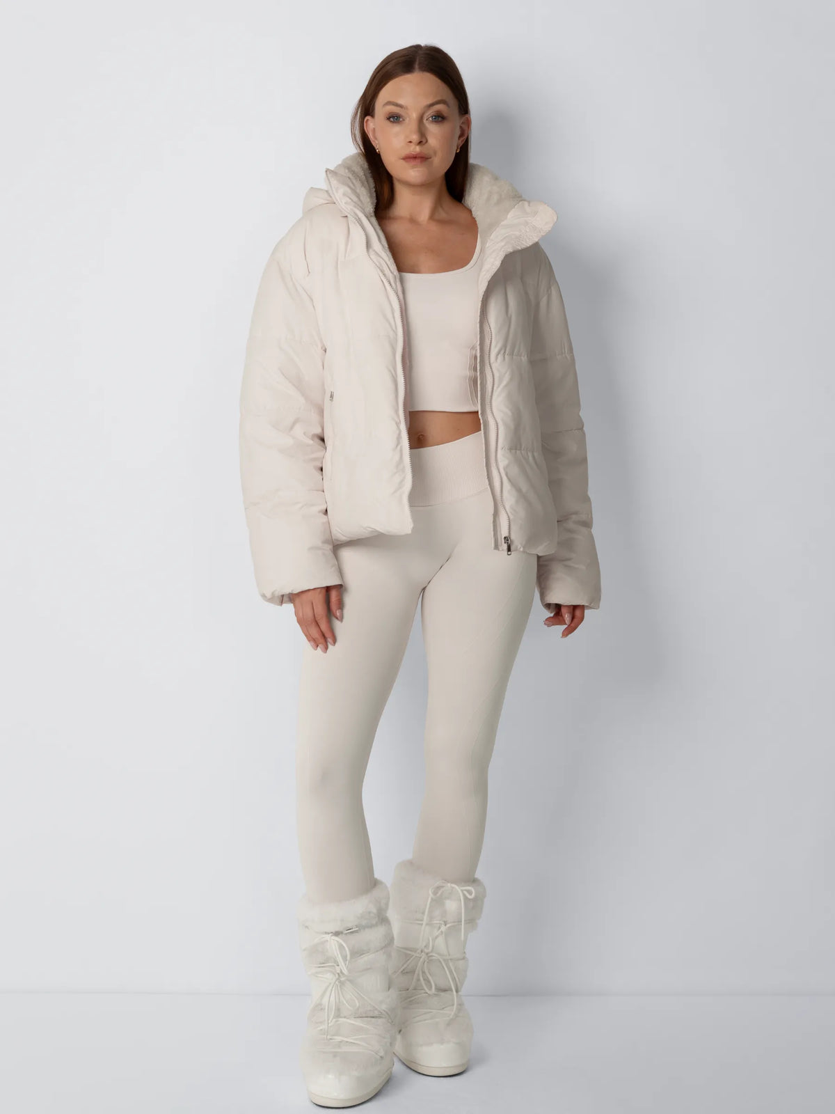 Full-length front view of the cream puffer jacket worn open with matching leggings and fluffy boots 5