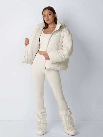 Model in cream puffer jacket holds it open to show the soft fleece lining, with fluffy cream boots 2