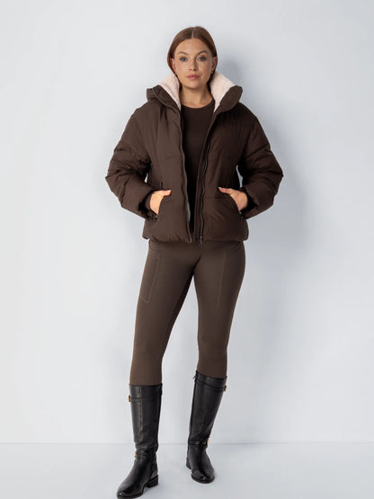 Full-length view of the dark brown puffer jacket with cream fleece lining, worn with brown leggings and black boots 15