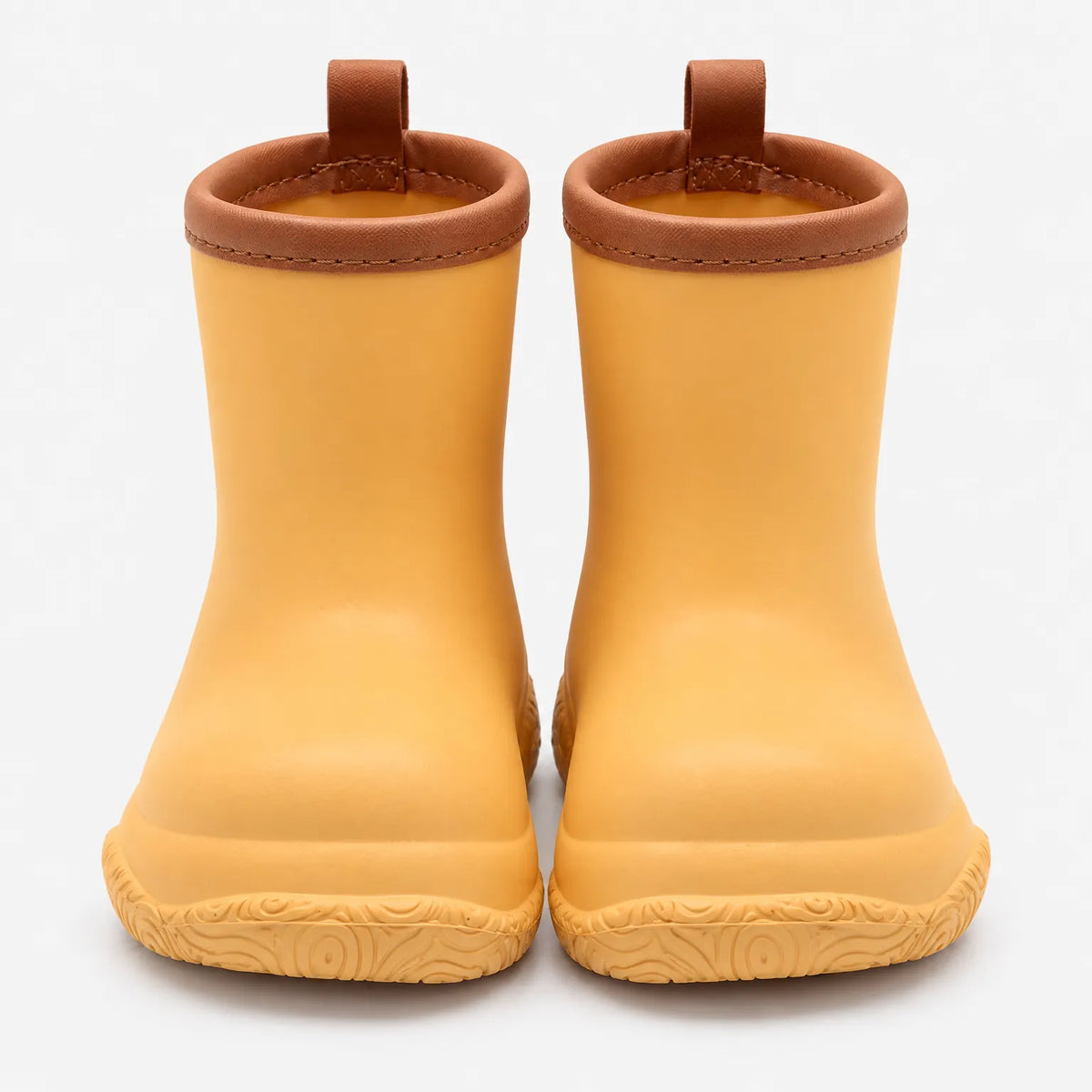 Front view of mustard yellow wellies with brown stitched collars and pull loops above a swirl-patterned sole. 11