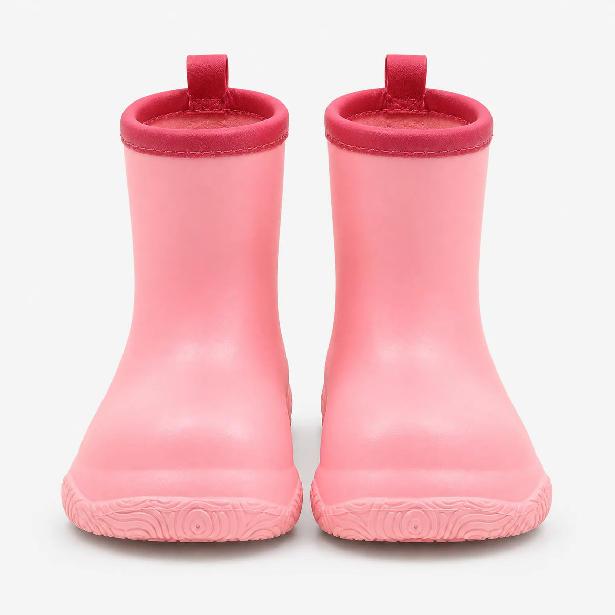 Pair of pink pull-on wellies seen straight on, with a deeper pink collar, pull loops and a swirl-patterned sole. 5