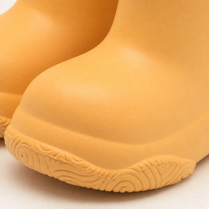 Close-up of the rounded toe and swirl-patterned sole of an orange welly, showing the smooth moulded finish. 6