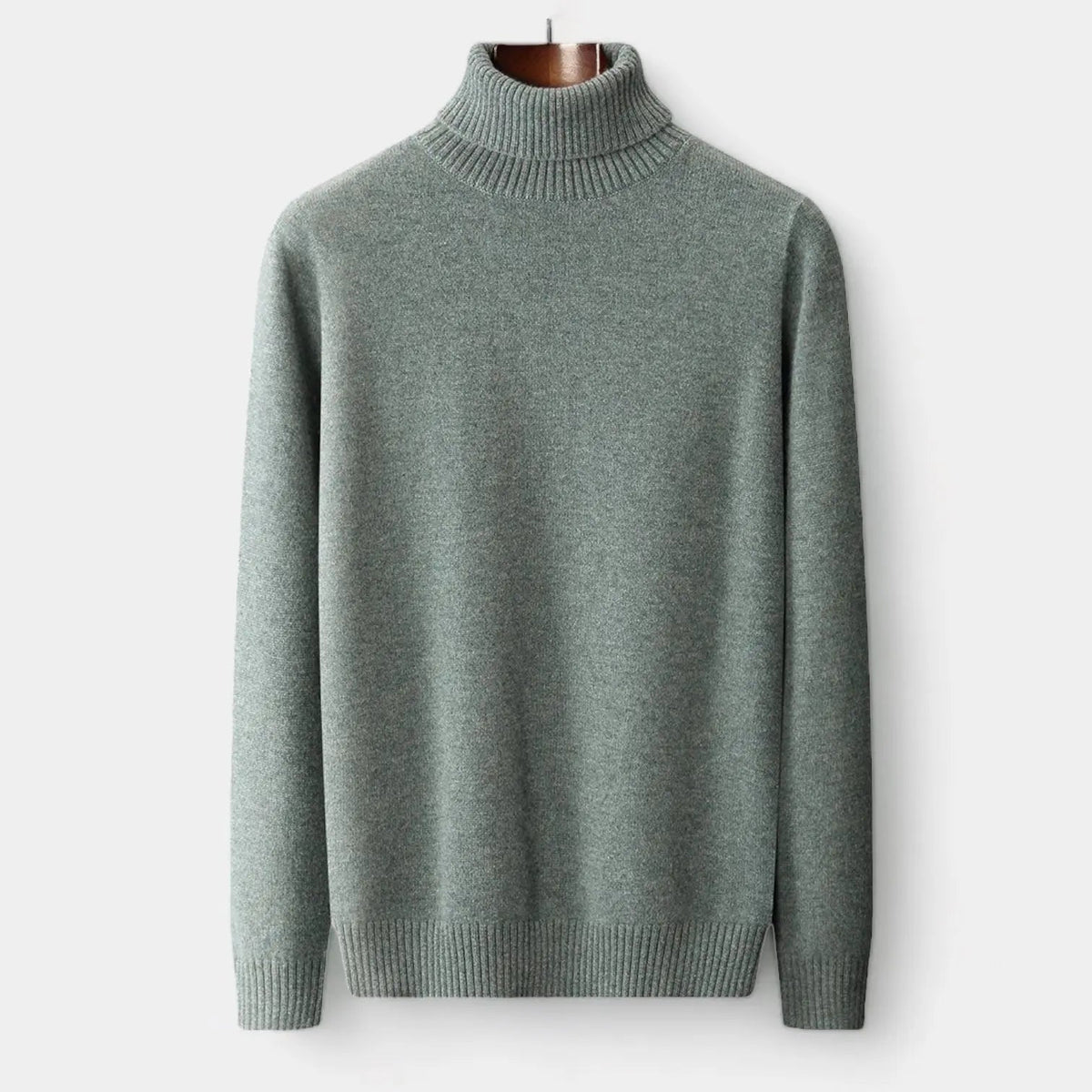 Front view of the sage green roll-neck jumper hanging on a wooden hanger, ribbed collar and cuffs 1