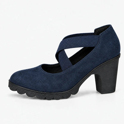 Single navy suede-look block heel with crossed elastic straps and scalloped black sole, shown in side profile on white. 12