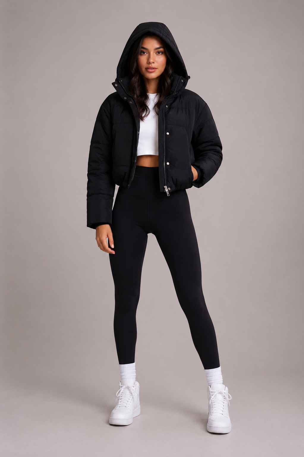 Full-length front view of the model wearing the jacket with the hood up and one hand in the pocket. 3