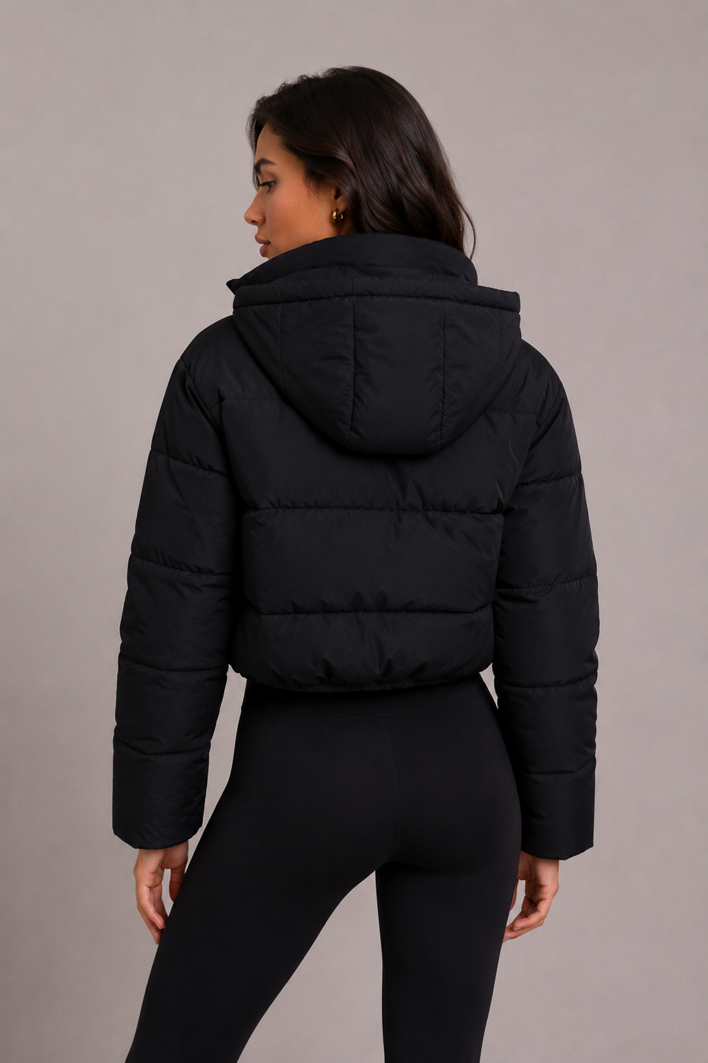 Back view of the black quilted jacket, showing the horizontal quilting and the hood folded down behind the collar. 4