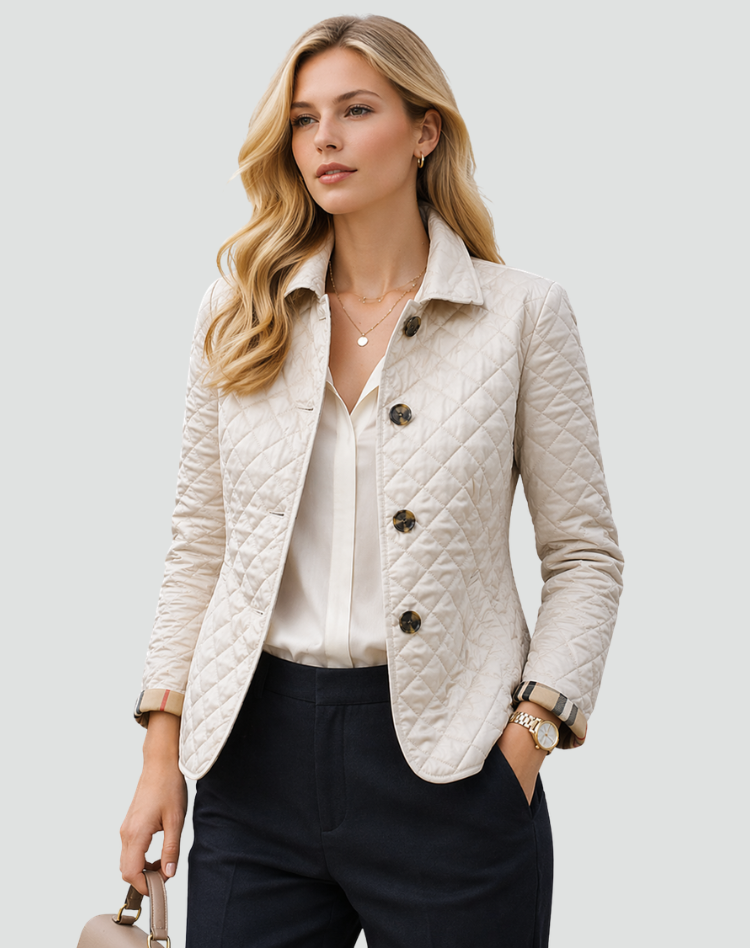 Model wearing the cream quilted jacket buttoned over a white blouse and navy trousers, holding a handbag, with checked cuffs turned back. 2