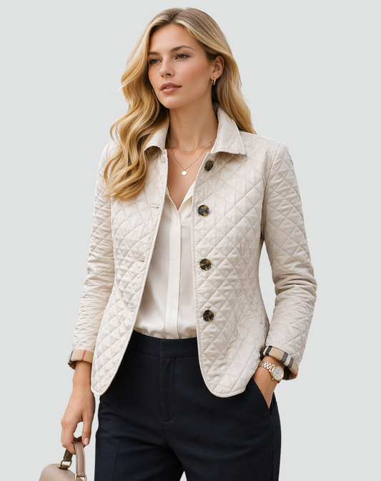 Model wearing the cream quilted jacket buttoned over a white blouse and navy trousers, holding a handbag, with checked cuffs turned back. 2
