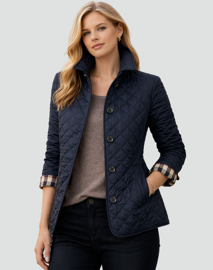 Model wearing the navy quilted jacket with a raised collar and checked cuffs, over a taupe top and dark jeans. 5