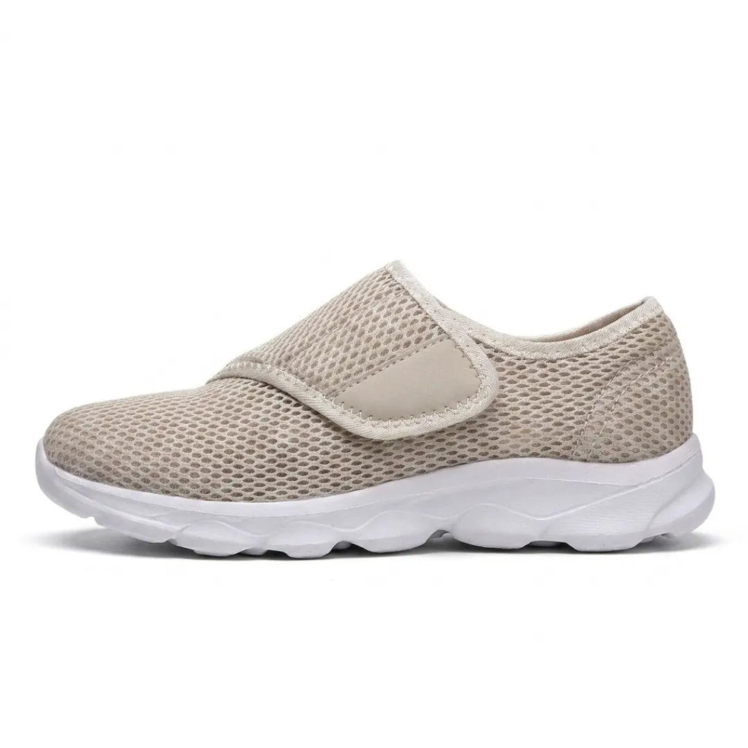 Side view of a single beige mesh shoe with white sole and hook-and-loop strap fastening across the instep. 28