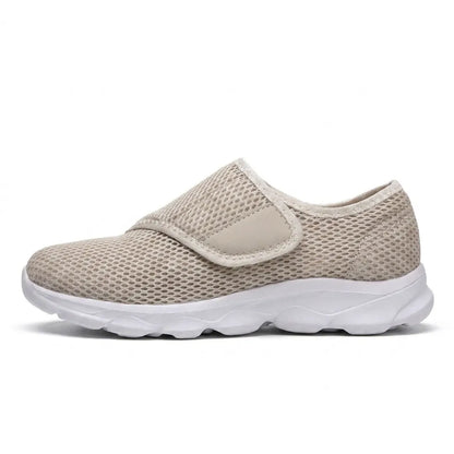 Side view of a single beige mesh shoe with white sole and hook-and-loop strap fastening across the instep. 28