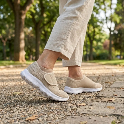 Person walking on a gravel park path wearing beige mesh shoes with white soles, beige socks and linen trousers. 29