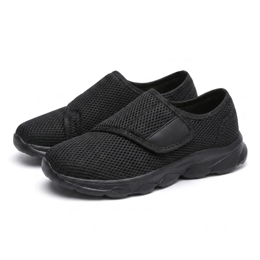 Pair of all-black mesh shoes seen from the front three-quarter angle, hook-and-loop straps fastened. 16