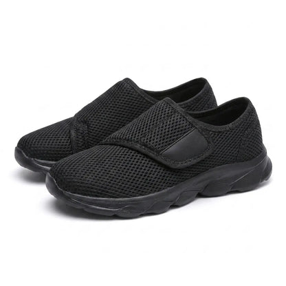 Pair of all-black mesh shoes seen from the front three-quarter angle, hook-and-loop straps fastened. 16