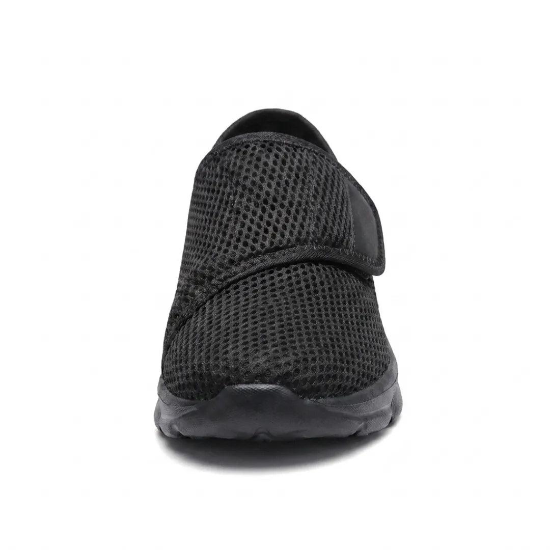 Front view of an all-black mesh shoe showing the rounded wide toe and the strap across the instep. 17