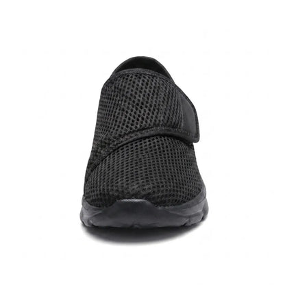 Front view of an all-black mesh shoe showing the rounded wide toe and the strap across the instep. 17