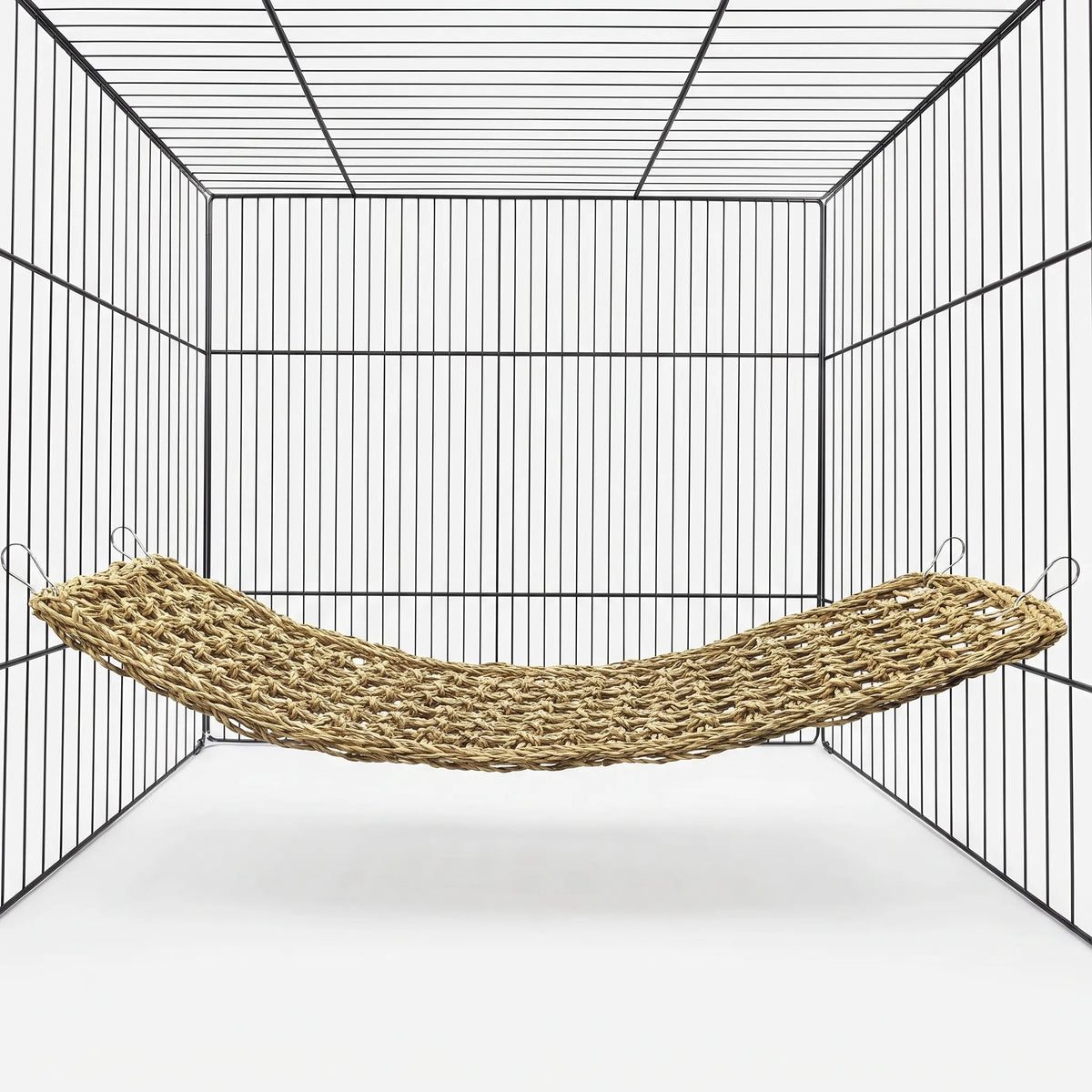 Empty woven natural-fibre hammock hung by four metal clips inside a black wire cage, shown against a plain white background. 1