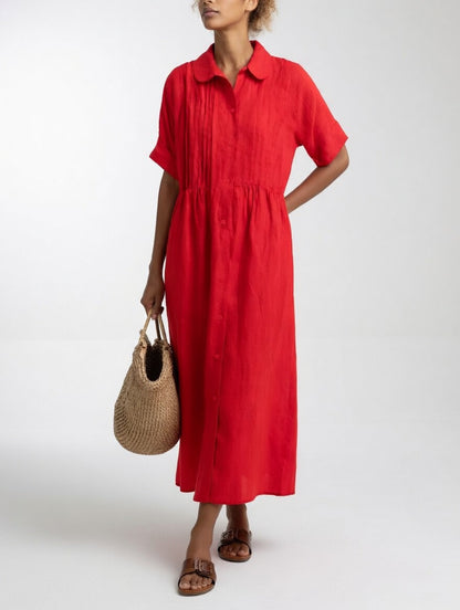 Model in the red dress with one hand behind her back, holding a straw tote, showing the long button front. 5