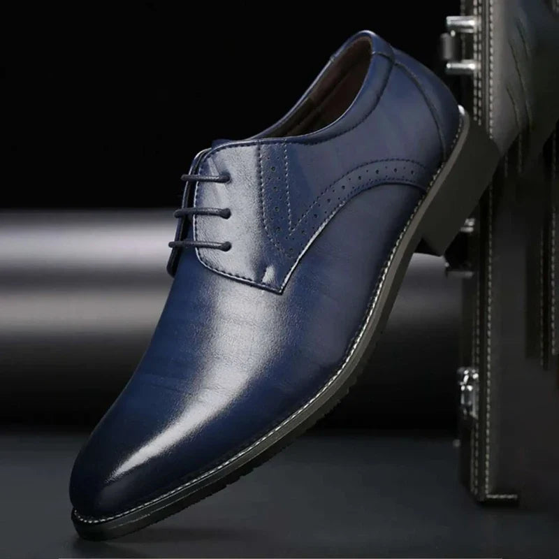Single navy blue polished lace-up shoe with brogue perforations, angled against a dark stitched case in a dark studio setting. 5