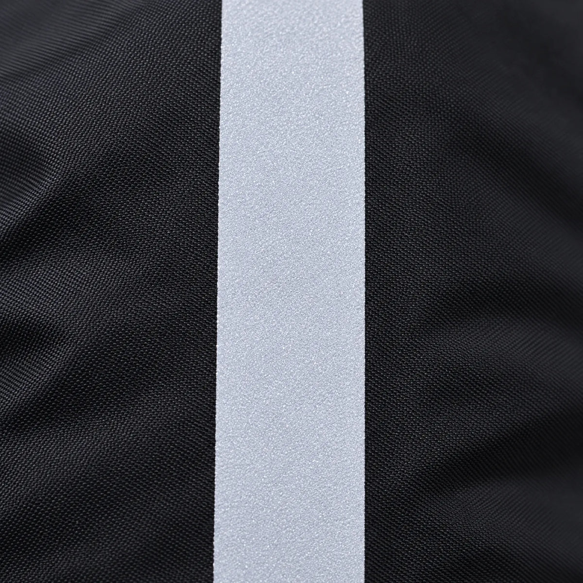 Close-up of the reflective strip on the black woven fabric, showing its fine, speckled, light grey surface. 5