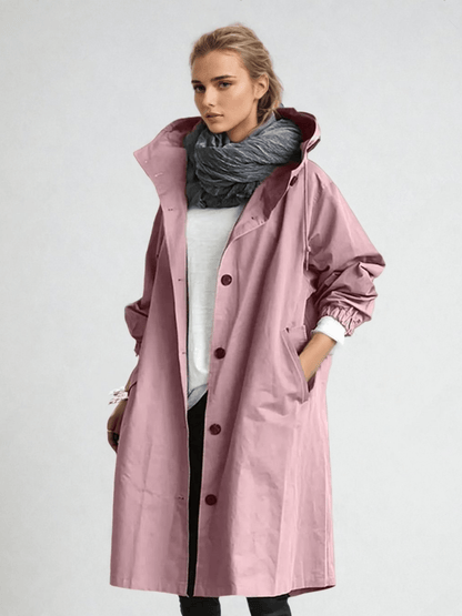 Model wears the long hooded coat in dusky pink, buttoned over a white top with a grey scarf and black trousers. 6