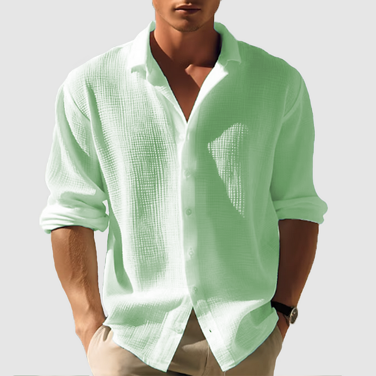 Model wearing the textured shirt in soft mint green, sleeves rolled up, front buttons fastened, hands tucked into beige trousers. 3