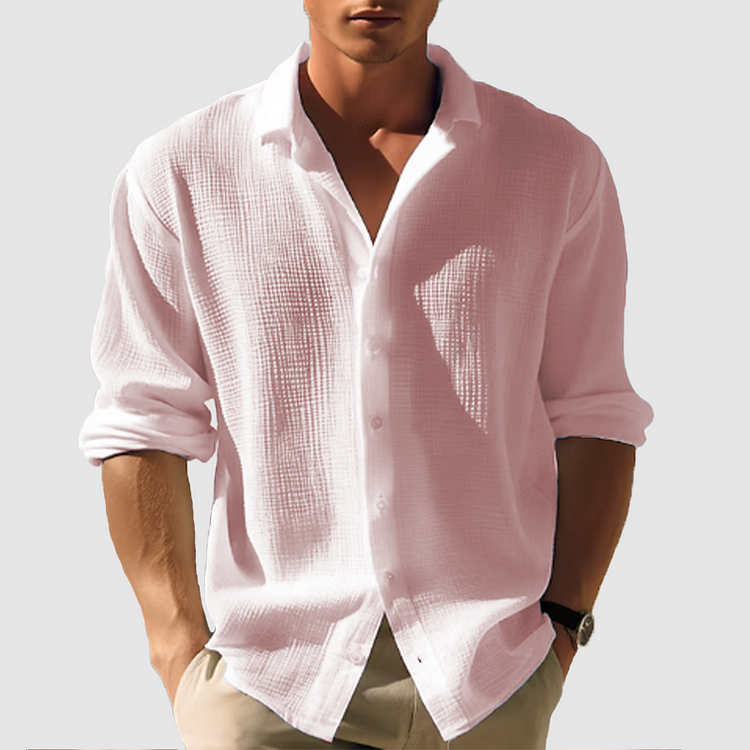 Model wearing the textured shirt in pale pink, rolled sleeves and open collar, shown front on with hands in trouser pockets. 4