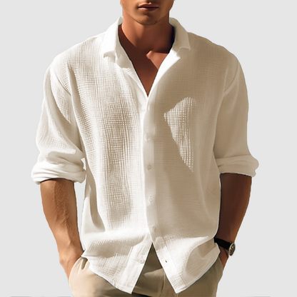 Model wearing the textured shirt in cream, sleeves pushed up to the forearms, relaxed fit with a crinkled weave, hands in pockets. 5