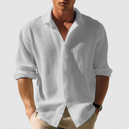 Model wearing the textured shirt in light grey, sleeves rolled up, open collar, crinkled fabric visible, hands in beige trousers. 6