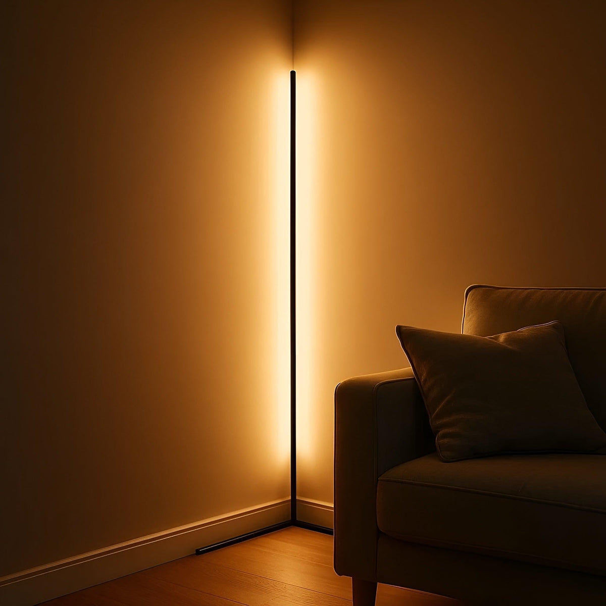 Black corner floor lamp shining a warm amber glow along two walls beside a sofa with a cushion in a dark room. 7