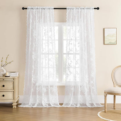 Pair of white floral lace curtain panels on a black rod in front of a window, in a cream-walled room. 6
